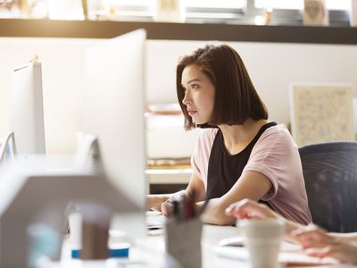 A woman looking at her PC intently while sitting at a desk.