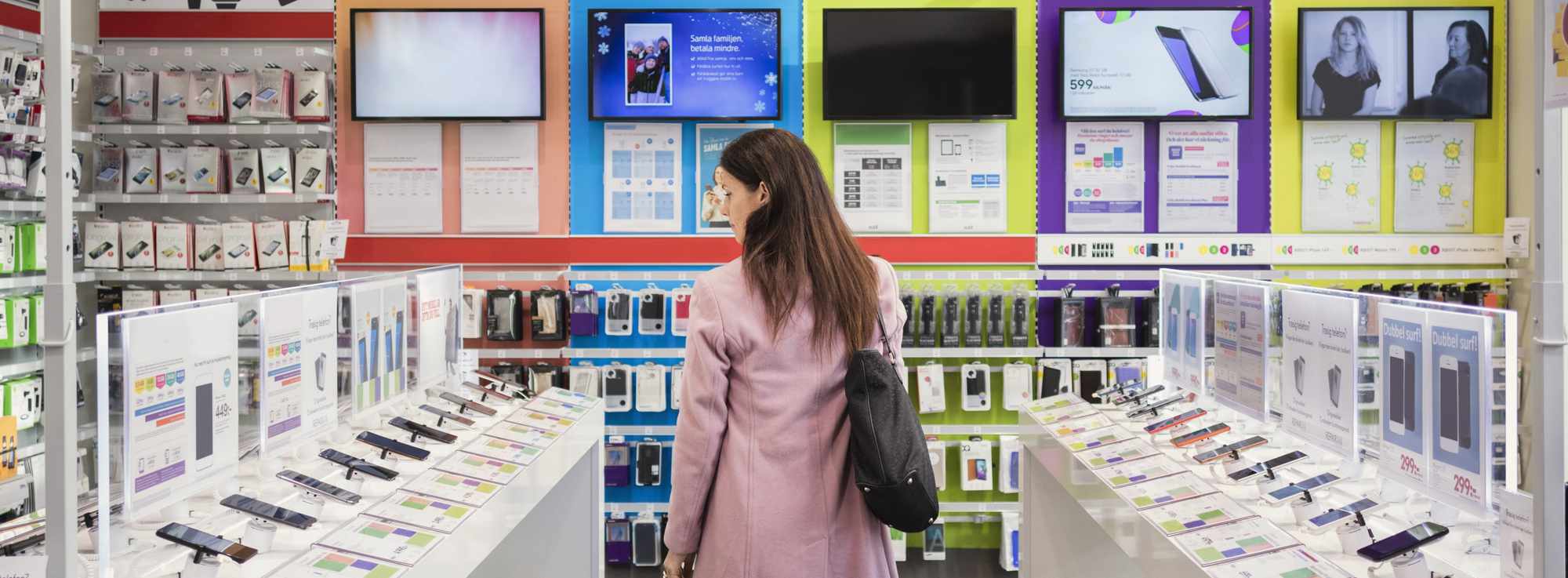 Woman walking through a store filled with technology.