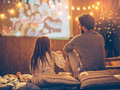 A father and daughter watching a movie outside.