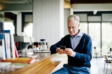 Man looking at his iPhone while sitting at a bar