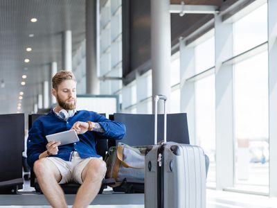 A man holding a Kindle checks his watch for the time.