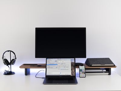 A MacBook pro displaying instructions with a blank monitor behind it on a riser. 