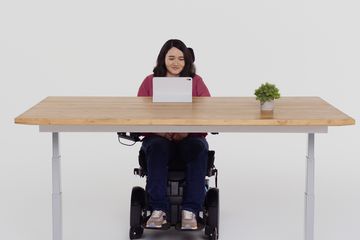 Person in a wheelchair using iPad eye control at a standing desk