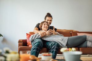 Young couple with smart phone relaxing on sofa.